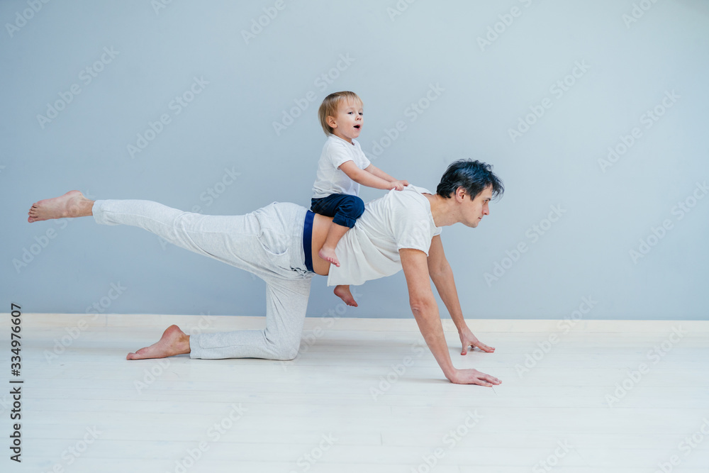 A sports man is engaged in fitness and yoga with a baby at home A sports man is engaged in fitness and yoga with a baby at home