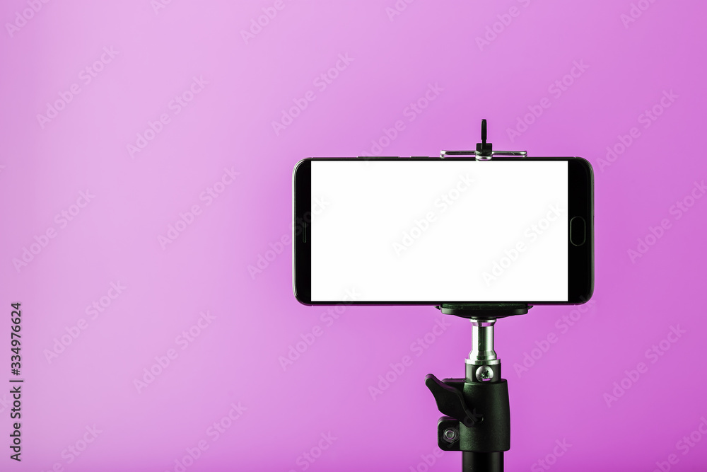 Mobile phone on a tripod with a clear white display for images and text, pink isolated background. Mobile phone on a tripod with a clear white display for images and text, pink isolated background.