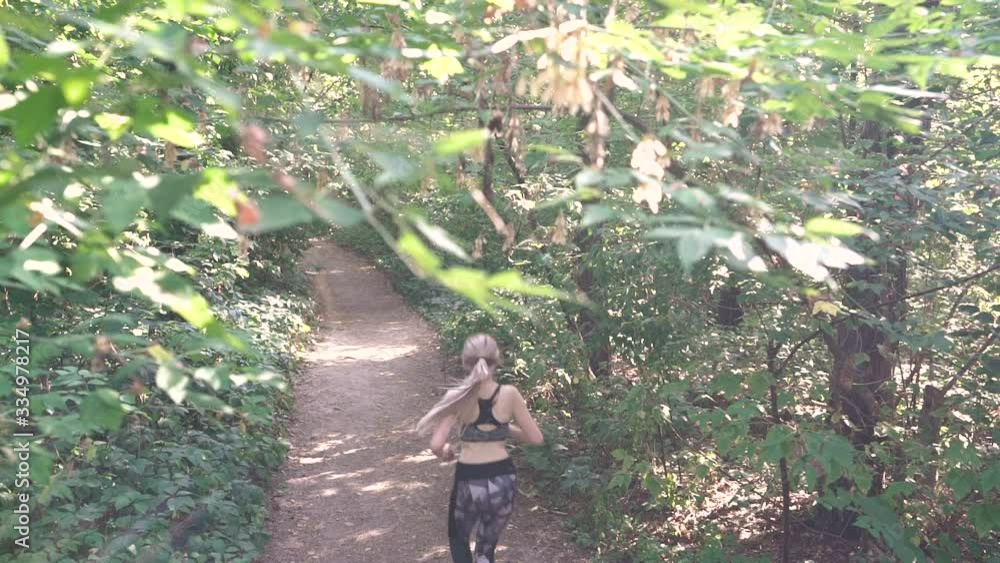 The unrecognizable girl runs in the forest blonde woman in sportswear camera movement slow motion The unrecognizable girl runs in the forest blonde woman in sportswear camera movement slow motion