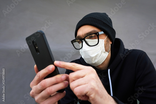 Coronavirus. A man in a protective mask with a phone in his hands. Covid 19. Pandemic 20. photo