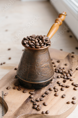 Turkish coffee pot full of coffee beans on wooden board