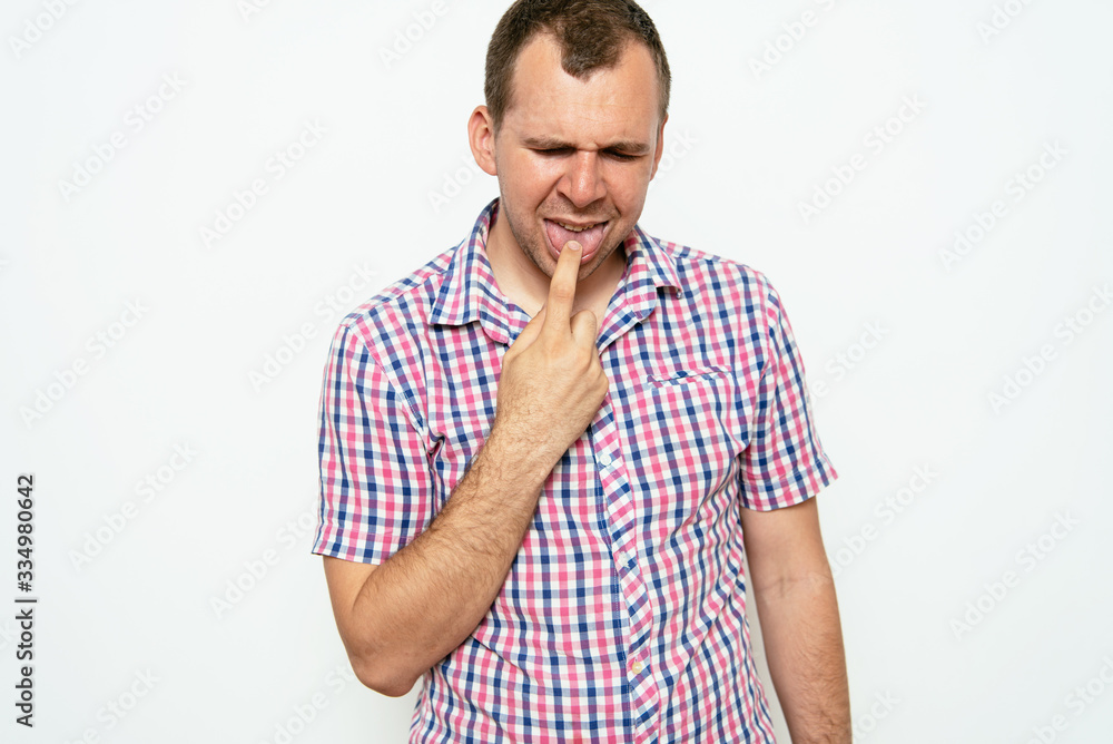 male of European appearance causes vomiting putting his fingers in his mouth on a gray background, nausea male of European appearance causes vomiting putting his fingers in his mouth on a gray background, nausea