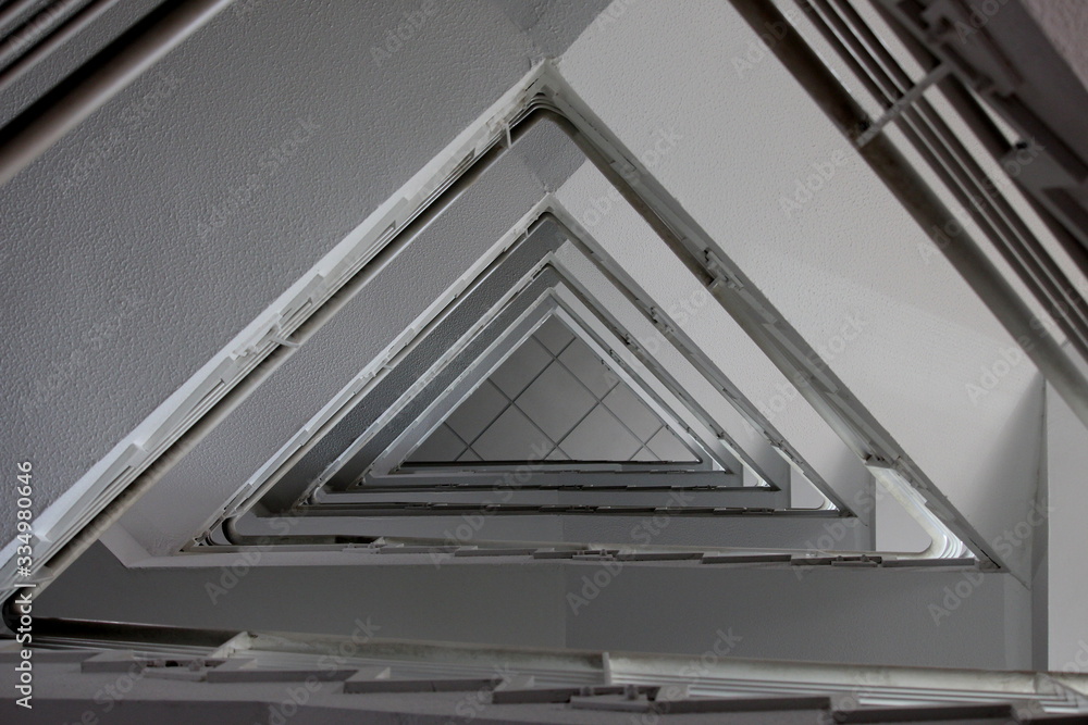 Fototapeta premium A photograph looking upwards in a stairwell, triangle geometric shape pattern. Internal building architecture