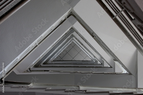 A photograph looking upwards in a stairwell, triangle geometric shape pattern. Internal building architecture