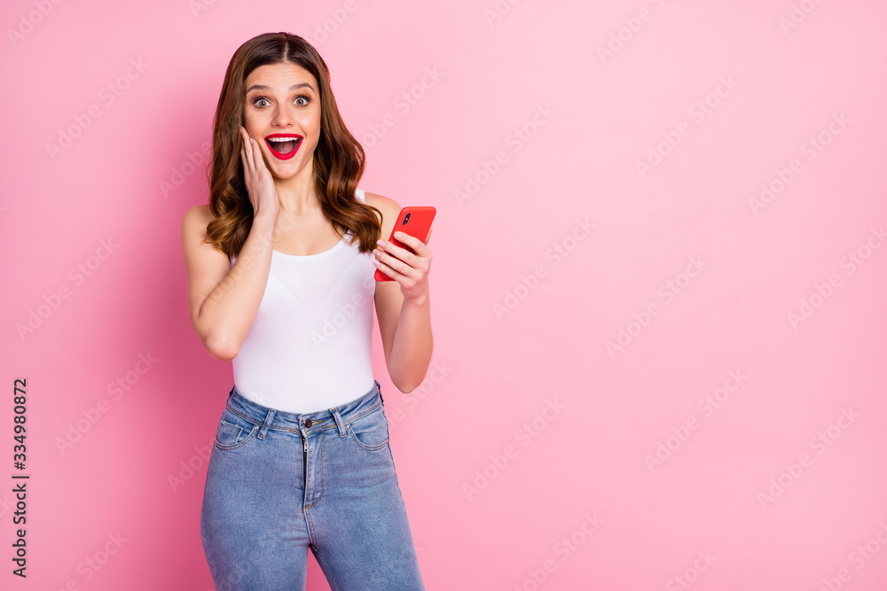 Portrait of excited energetic girl use cellphone read social media news impressed by like followers subscribers wear white singlet isolated over pink color background Portrait of excited energetic girl use cellphone read social media news impressed by like followers subscribers wear white singlet isolated over pink color background
