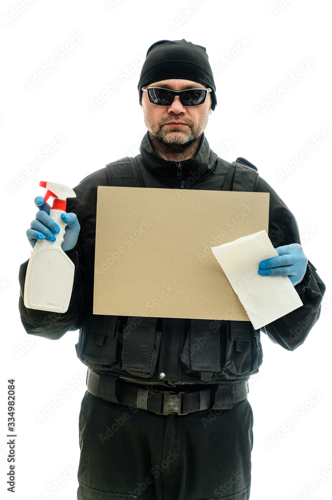Concept Isolated portrait on a white background man in black police special forces uniform in medical gloves and cleaning supplies and banner in hands Concept Isolated portrait on a white background man in black police special forces uniform in medical gloves and cleaning supplies and banner in hands