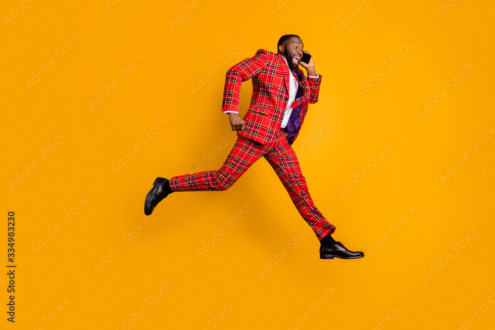 Discounts i hurrry. Full size profile side photo crazy funky dark skin guy pause break jump up use cellphone tell say run runner wear red plaid pants tie tuxedo isolated yellow color background