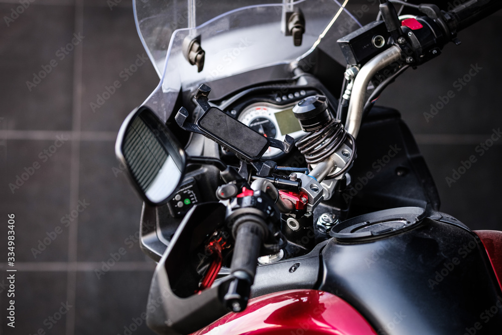 Motorcycle details close up. Motorbike speedometer, warning lights, mirror, tank, mobile device holder. Black motorbike with red details parked in the city. Close up, copy space, selective focus