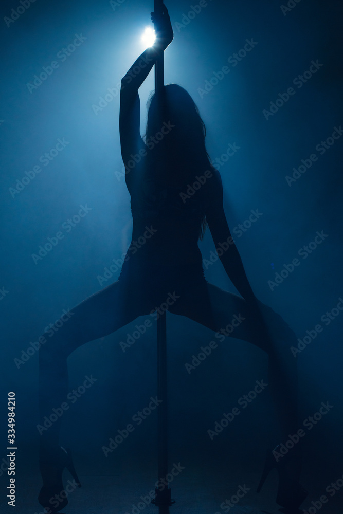 Silhouette of a girl standing near the pole. Blue background.