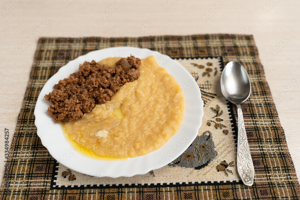 Yellow pea puree with meat in a white plate