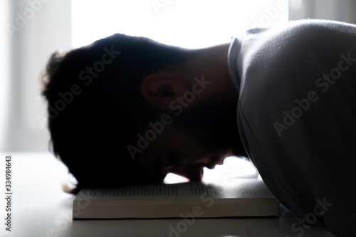 Fotografie Student tired of studying sleeping with his head on a book