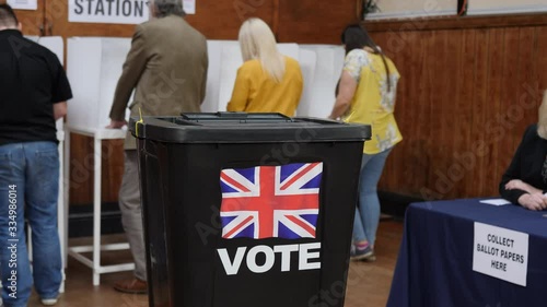 4K: Voter inserts ballot paper into box at a Polling place - They are voting in the UK at an election and making their choice. Vote. Stock Video Clip Footage photo