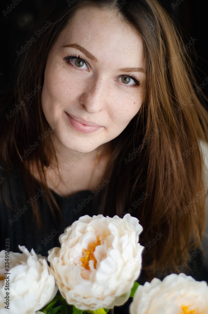 photo of a young beautiful girl in black in a room with flowers