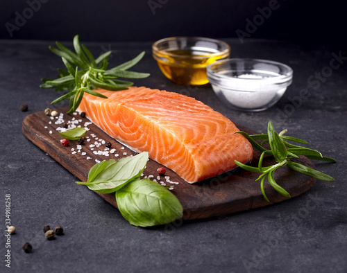 Salmon fish on the stone with fresh rosemary, basil and spices. Steak on black background.