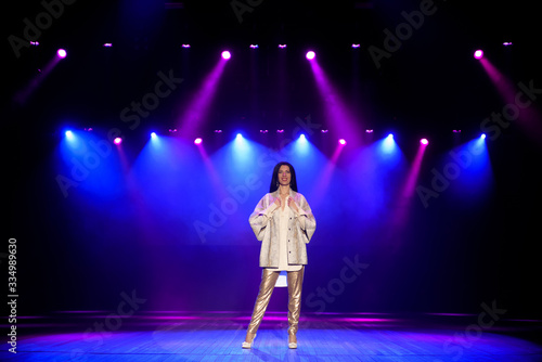 Actress on the stage in colorful bright beams of light.