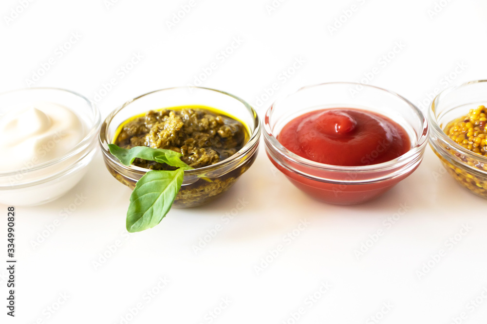 Close-up various sauce and dip with selective focus on white background. Mayonnaise, pesto, ketchup and french mustard in glass bowls Close-up various sauce and dip with selective focus on white background. Mayonnaise, pesto, ketchup and french mustard in glass bowls