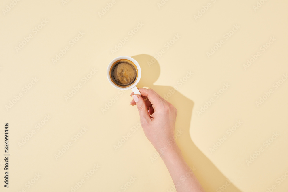 cropped view of woman holding cup of fresh coffee on beige background cropped view of woman holding cup of fresh coffee on beige background