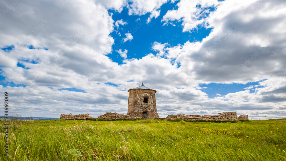 the tower and the ruined walls of the ancient fortress in Elabuga, clouds in the blue sky, steppe grass bending in the wind the tower and the ruined walls of the ancient fortress in Elabuga, clouds in the blue sky, steppe grass bending in the wind