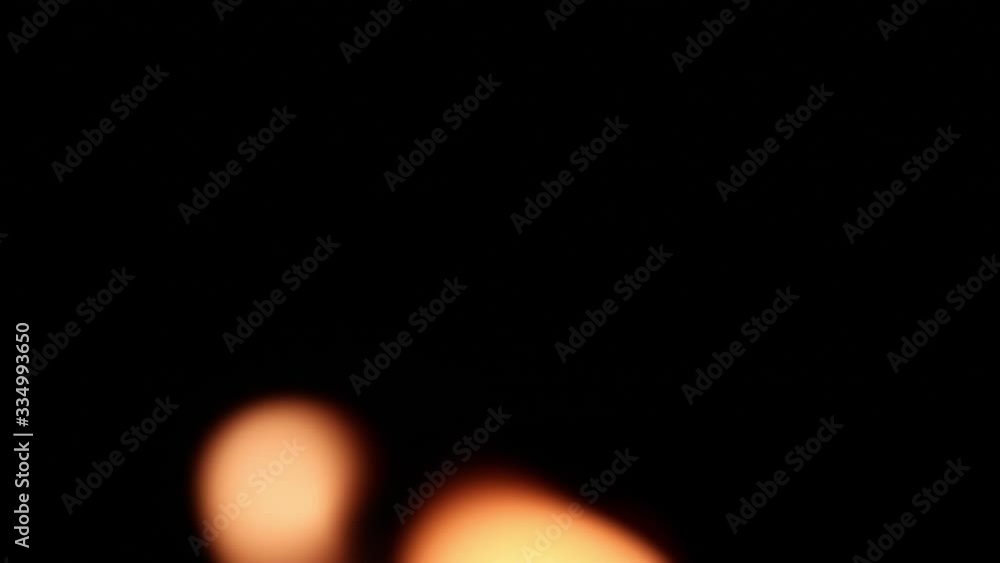 Close-up of blurred burning candle flames blinking and swaying in the wind at night Close-up of blurred burning candle flames blinking and swaying in the wind at night