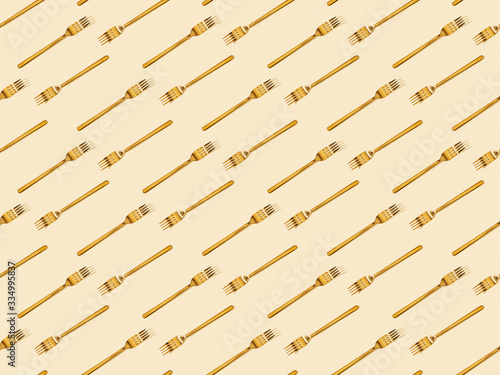 Fotografie top view of golden forks isolated on beige, seamless background pattern