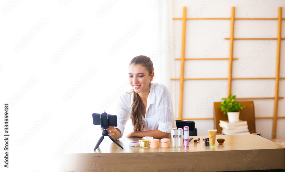 Oner business sme concept. Young female blogger with makeup cosmetics recording video at home. Work from home and social distancing concept Oner business sme concept. Young female blogger with makeup cosmetics recording video at home. Work from home and social distancing concept