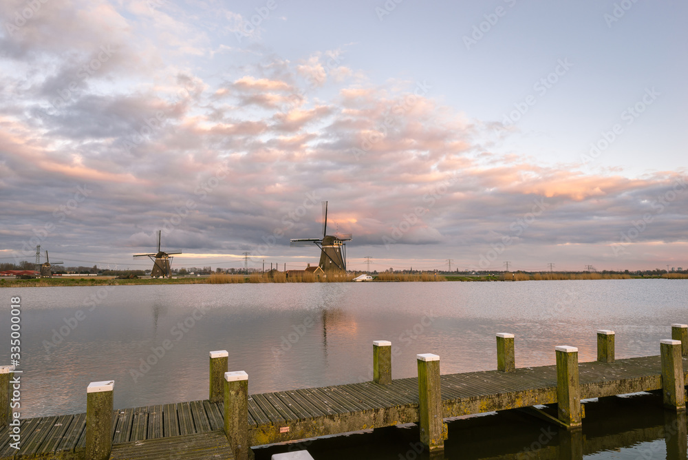 Windmills at the shore of a lake in Holland under a beautiful evening sky