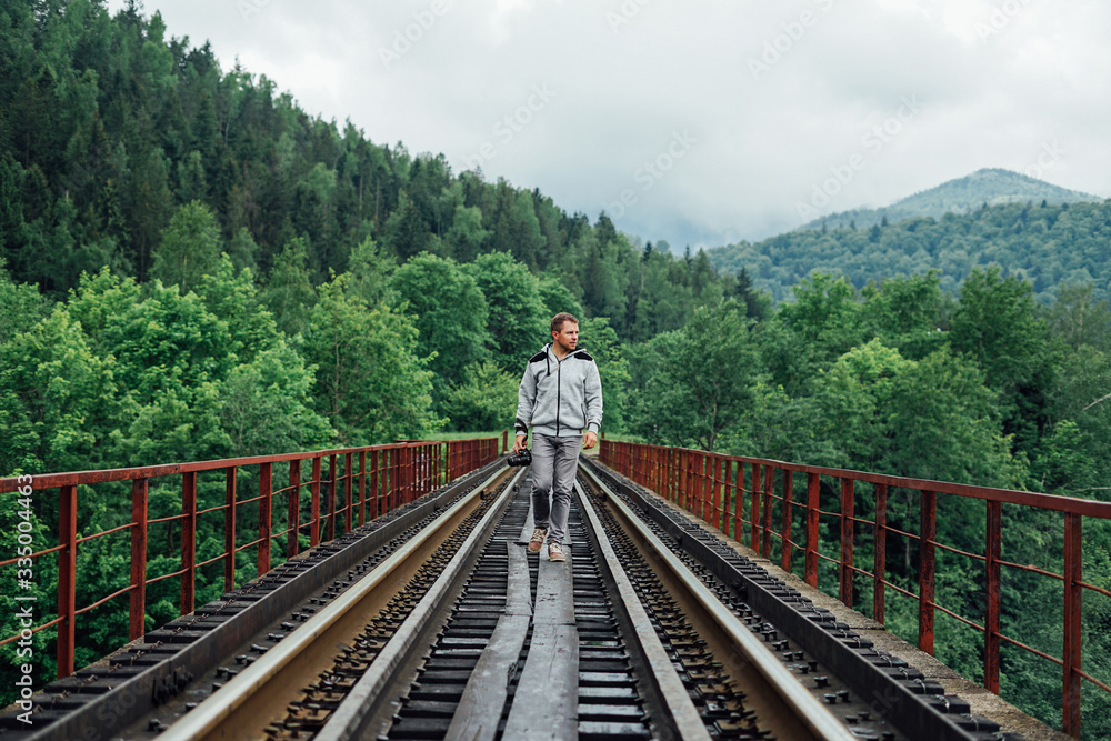Fototapeta premium Young man in a gray tracksuit on a railway track.