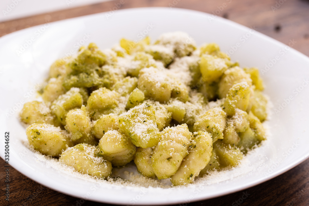 Italian homemade gnocchi with basil sauce and potatoes. Traditional dish of Italian cuisine, vegetarian food.