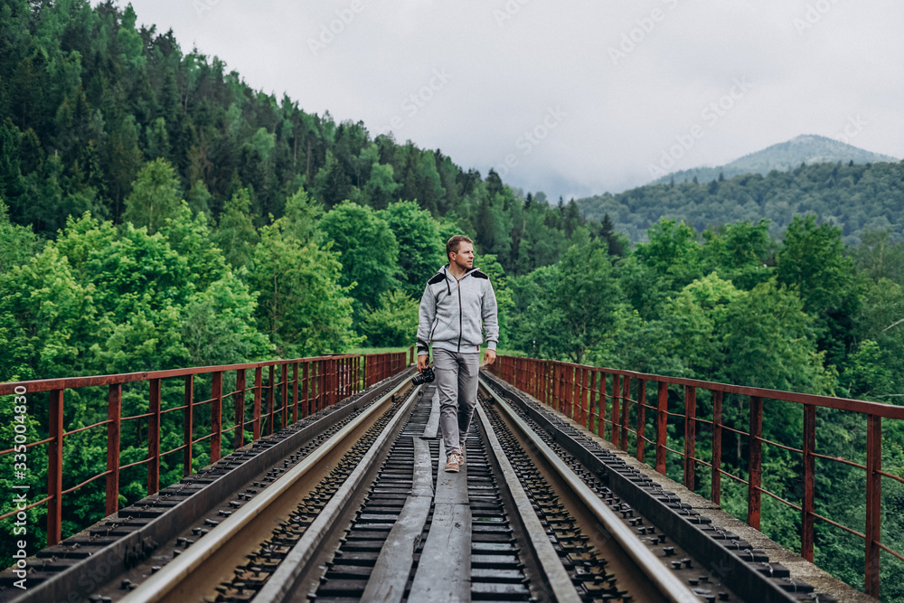 Young man on railway track on forest background