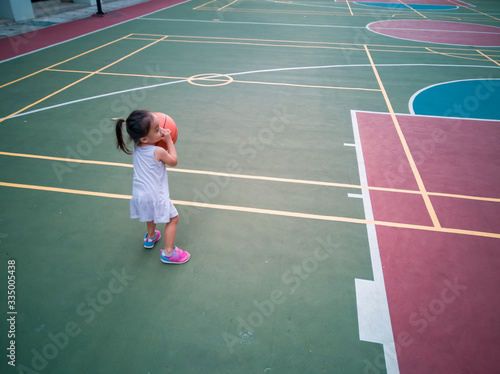 Asian Toddler playing basketball at the basketball court in the evening. © ellinnur