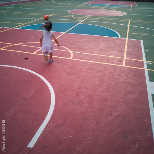 Asian Toddler playing basketball at the basketball court in the evening. © ellinnur