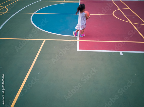 Asian Toddler playing basketball at the basketball court in the evening. © ellinnur
