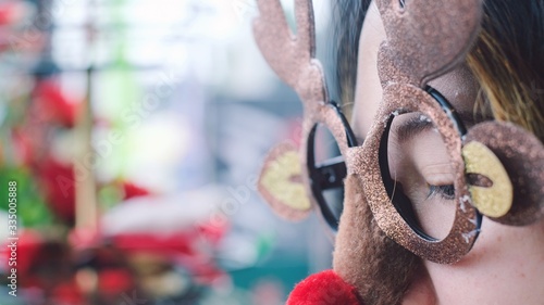 Close up young woman wearing funny Christmas party deer glasses with red nose .Holiday Christmas concept.