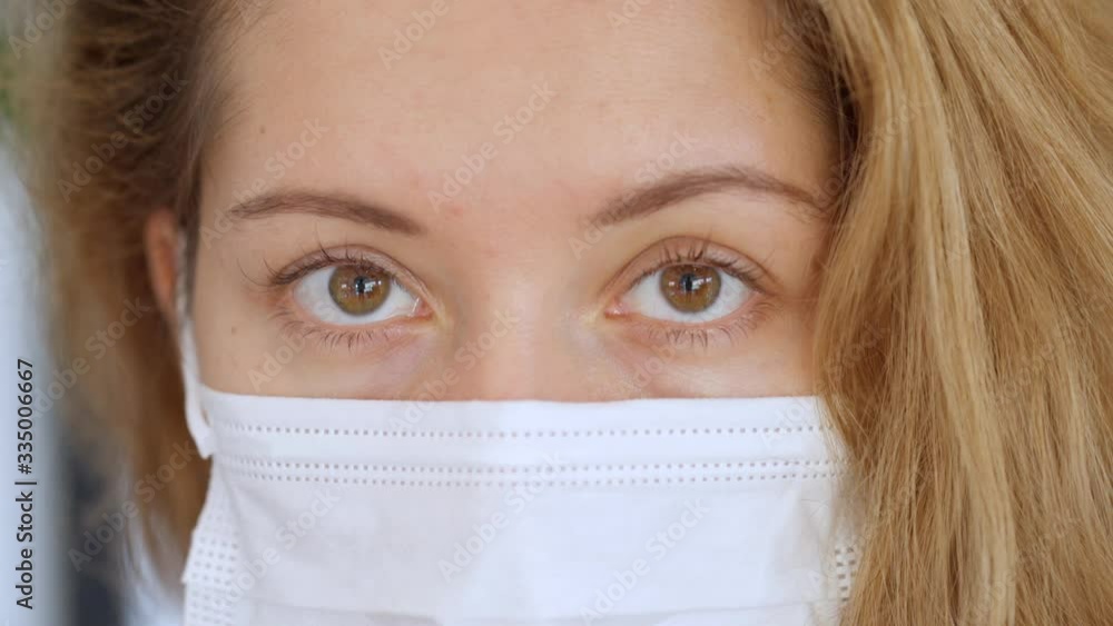 close up portrait of Young Woman wearing white protective mask looks at camera close up portrait of Young Woman wearing white protective mask looks at camera