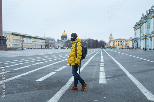Young man in yellow jacket walking on the road. Empty dvortsovaya square in the centre on self isolation photo