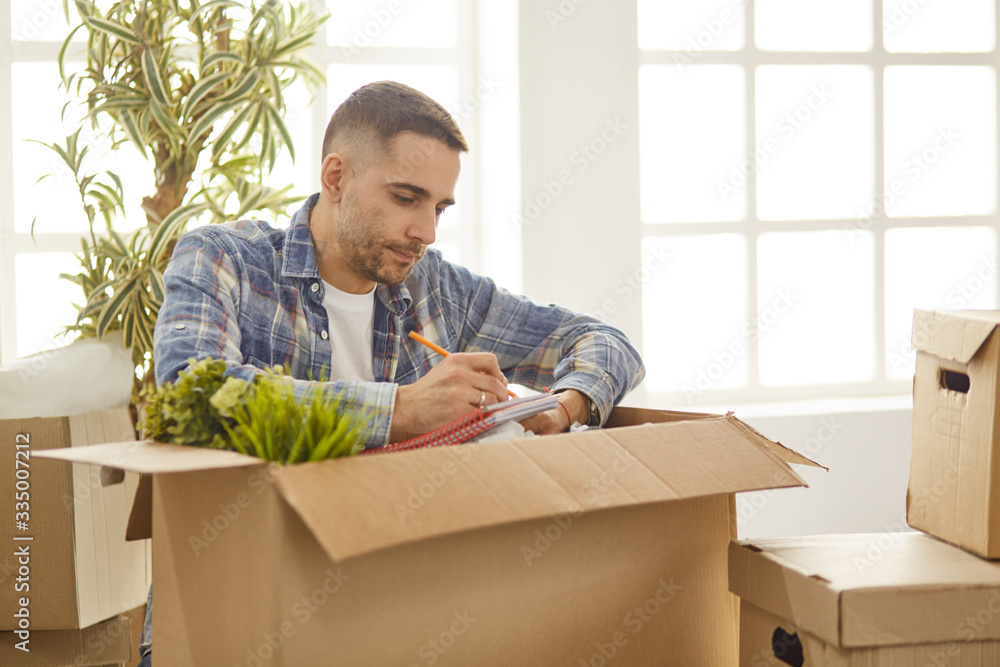 Handsome man with boxes in the new apartment after moving Handsome man with boxes in the new apartment after moving