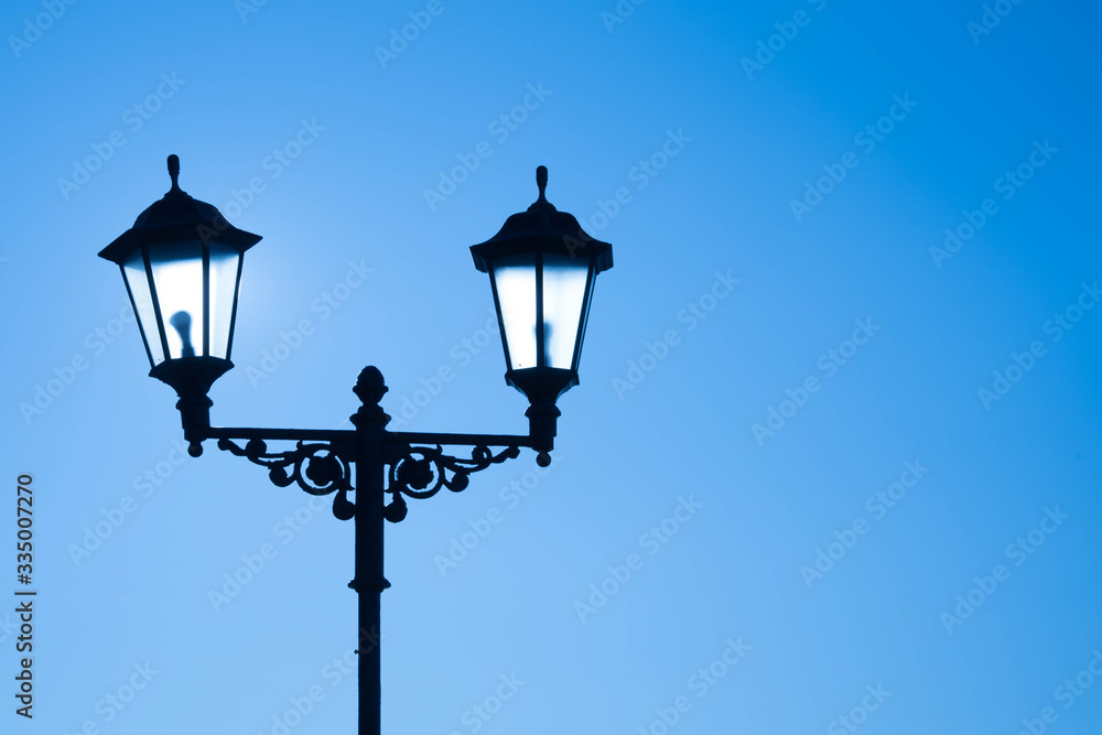 Urban landscape. Street lamp with a lamp in a classic style against a purple sky. Beautiful postcard.