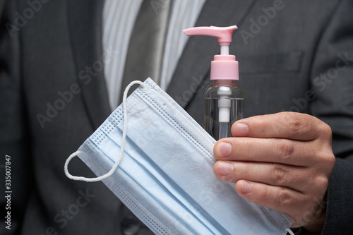 a man demonstrates a protective face mask for antivirus individual protection and bottle of sanitizer liquid- healthcare and medicine concept, prevention tips photo