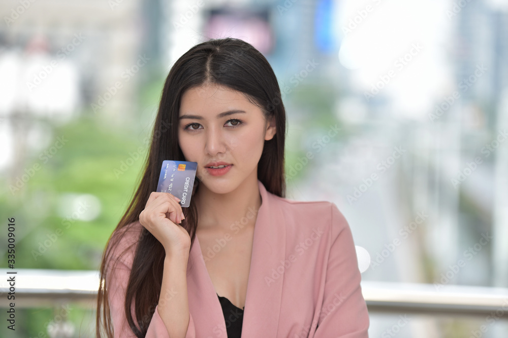Asian girl in pink suit Send a sweet smile to a hand holding a credit card. Beautiful businesswoman in suit Asian girl in pink suit Send a sweet smile to a hand holding a credit card. Beautiful businesswoman in suit
