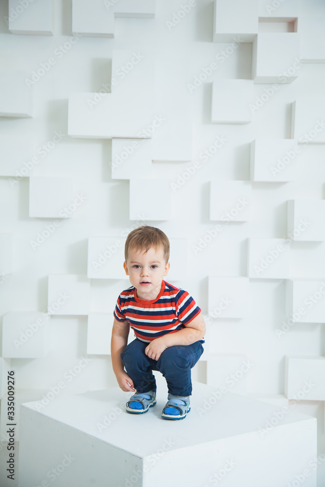 Toddler boy sit on white cube at studio. Toddler boy sit on white cube at studio.