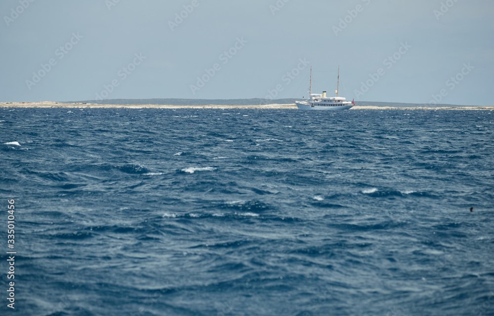 Obraz premium The landscape of the balearic sea, azure water, sunny weather, is a lonely sail boat is on the horizon