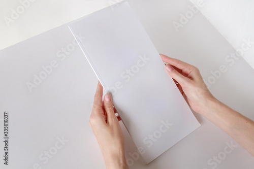 White booklet mockup. Vertical format blank booklet. A woman holds an album with blank pages. Blank cover mocku