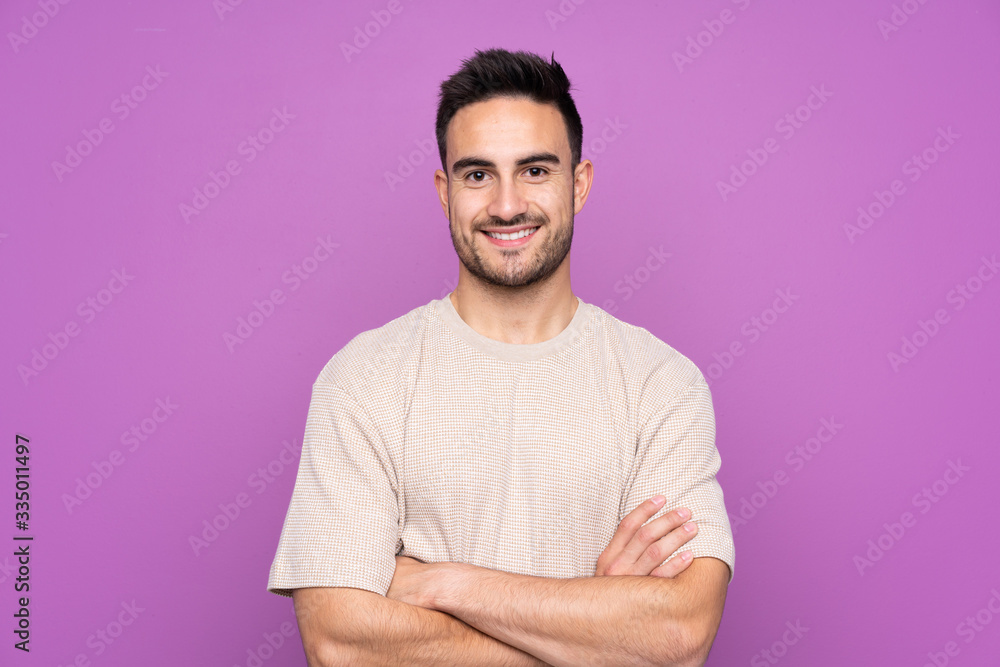 Young handsome man over isolated purple background keeping the arms crossed in frontal position Young handsome man over isolated purple background keeping the arms crossed in frontal position
