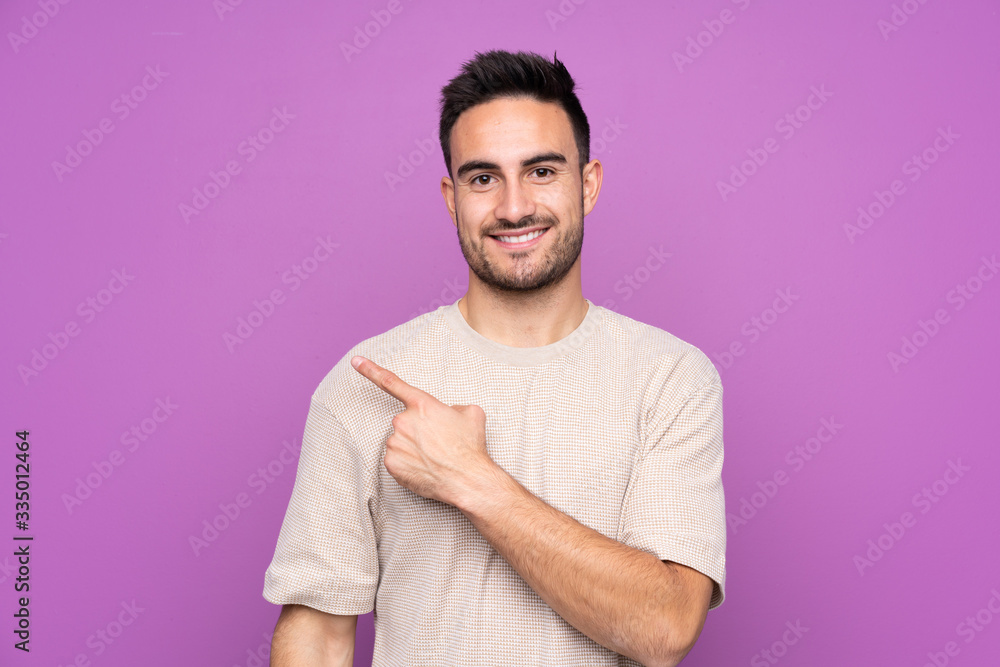 Young handsome man over isolated purple background pointing to the side to present a product Young handsome man over isolated purple background pointing to the side to present a product