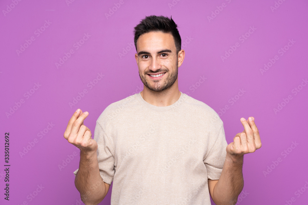Young handsome man over isolated purple background making money gesture Young handsome man over isolated purple background making money gesture