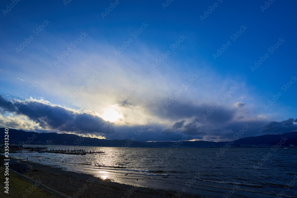 Lake in a windy day, landscape where sunlight can be seen through a gap in a cloudy sky. Lake in a windy day, landscape where sunlight can be seen through a gap in a cloudy sky.