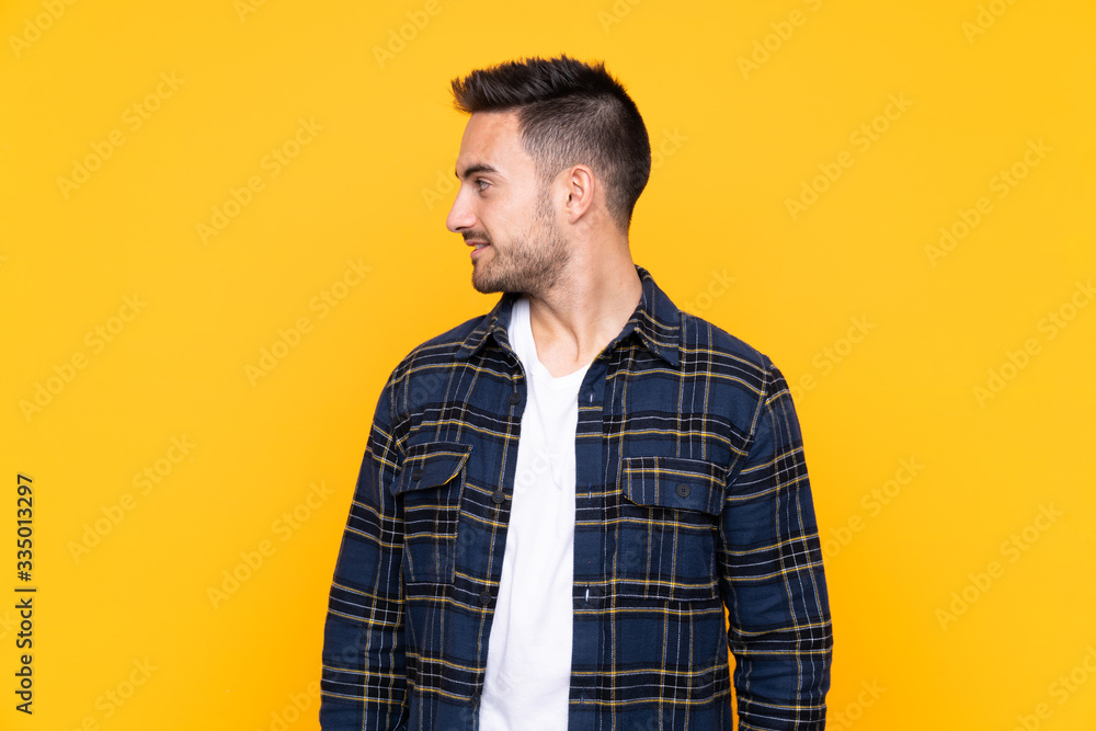 Young handsome man over isolated yellow background looking to the side Young handsome man over isolated yellow background looking to the side