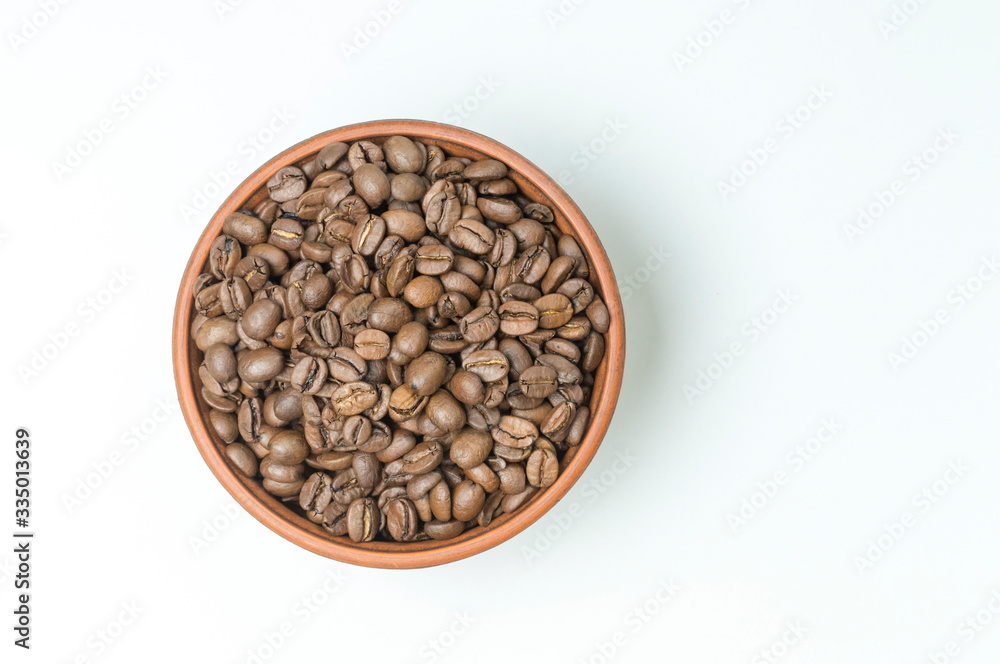 Fototapeta premium roasted coffee beans in a clay Cup on a white background top view