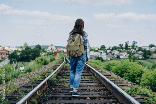 Young woman with a backpack on a railway track. Railroad track on city background