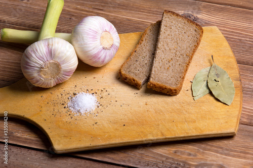 fresh garlic on a wooden board, brown bread and salt